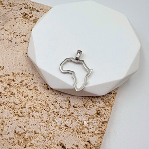A sterling silver pendant in the shape of the outline of Africa, displayed on a white stand with a textured background.