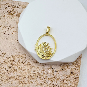 A sterling silver gold plated pendant in the shape of a Protea flower adorned with zirconias, displayed on a white stand.
