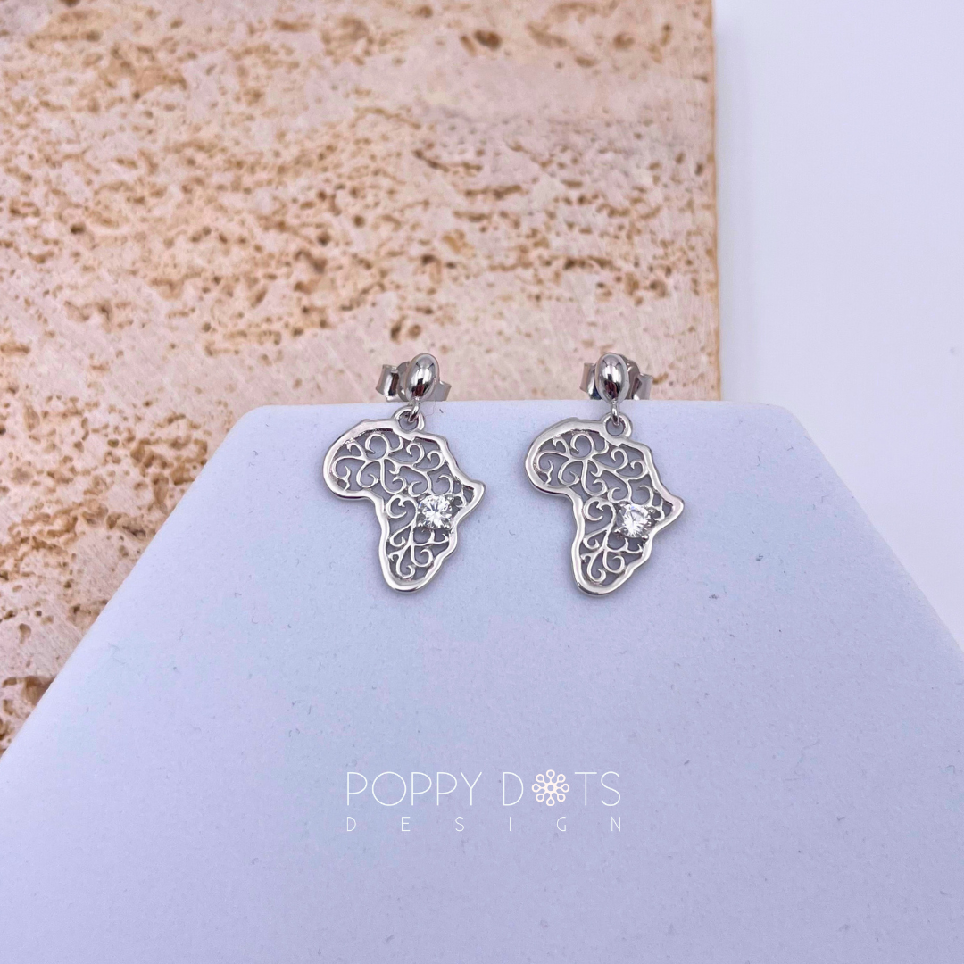 A pair of sterling silver filigree zirconia Africa earrings displayed on a stand with a textured background.